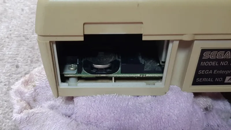 セガサターン本体背面の電池交換部分を開いた様子（CR2032が装着されている状態）